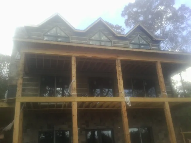 Dormers and porch framing on a large log home under construction — Roof Coating work by our crew in Fort Myers Beach