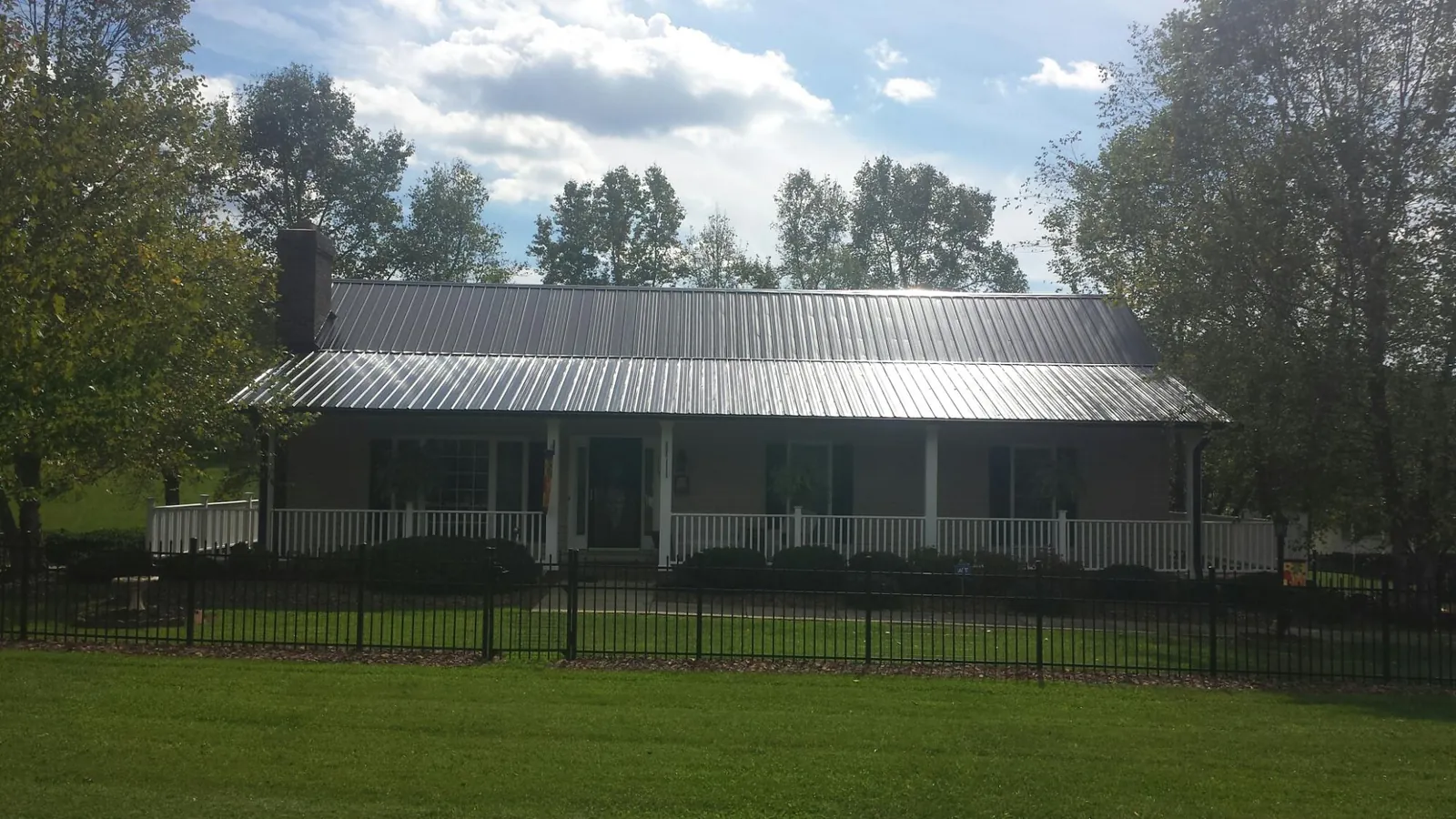 Gray metal roof on a brick ranch with a full width front porch — Gutter Guard Installation work by our crew in Fort Myers Beach