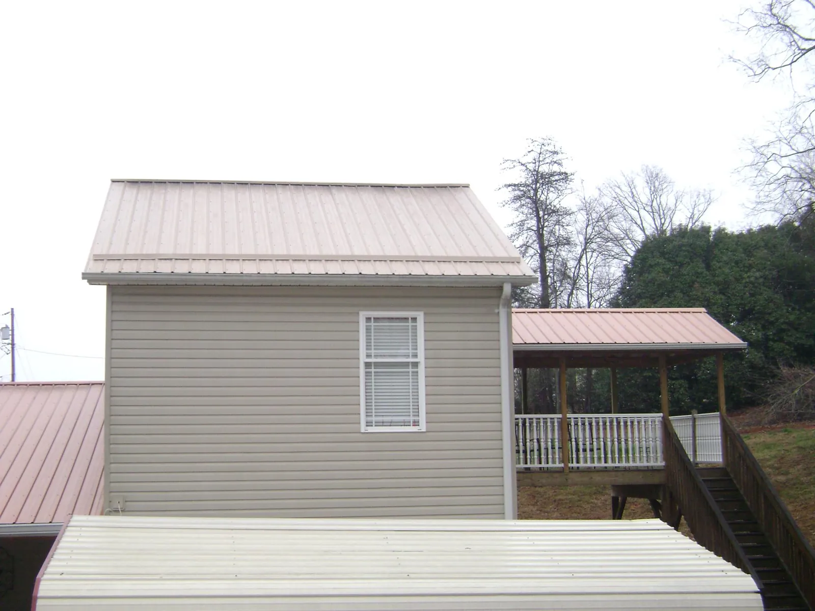 Tan metal roofs on a two story addition and attached porch, from a Roof Replacement job in Fort Myers Beach
