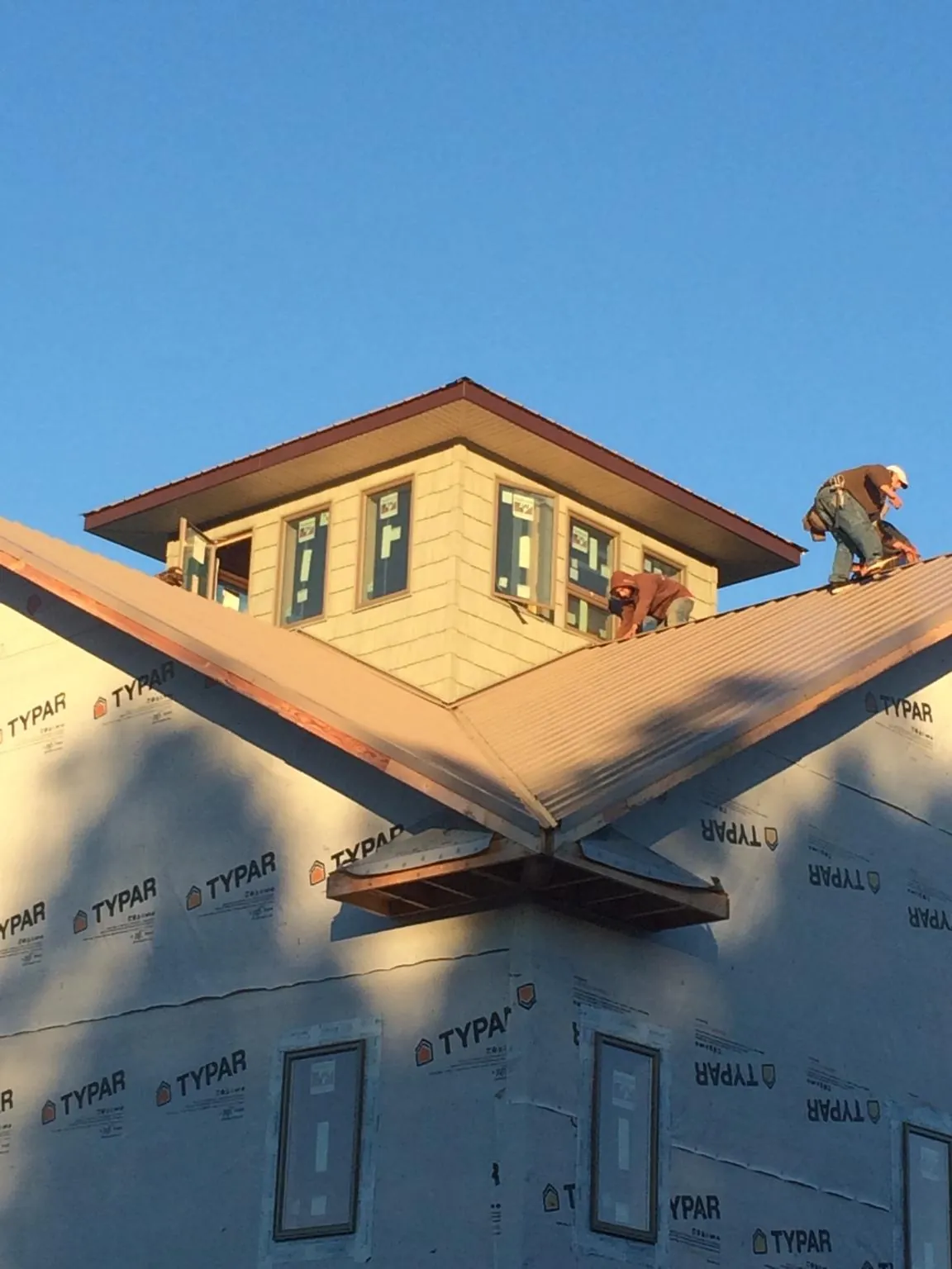 Roofers working around a rooftop cupola on a new metal roof at sunset — Roof Waterproofing in Fort Myers Beach by Roofing Brothers